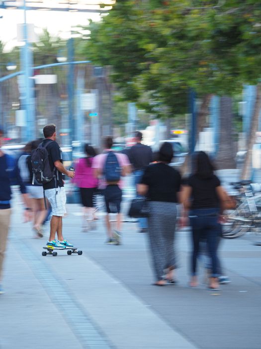 Skate boarder moving fast amongst the pedestrians